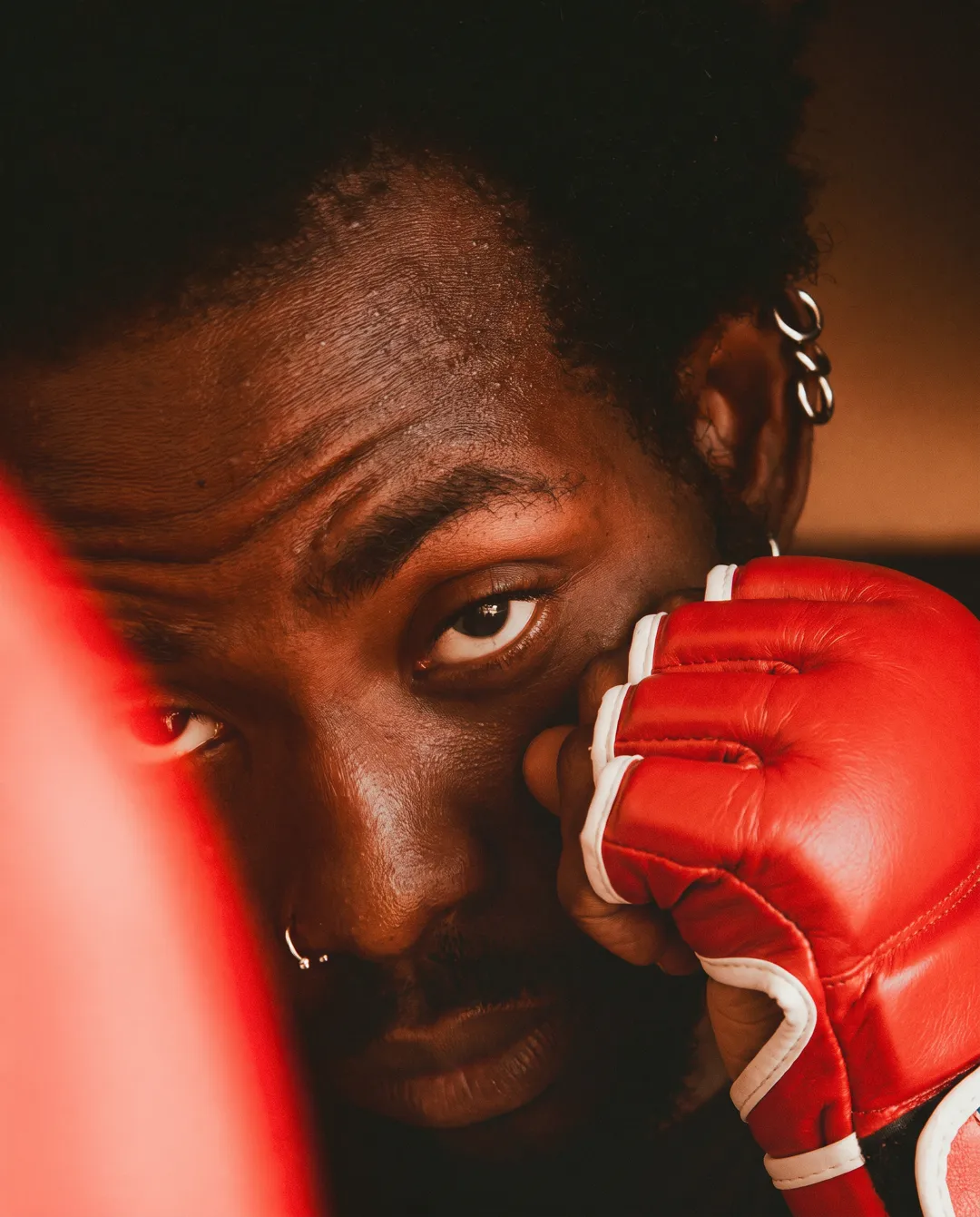 Regard d'un combattant derrière son gant rouge, club de MMA La Forge