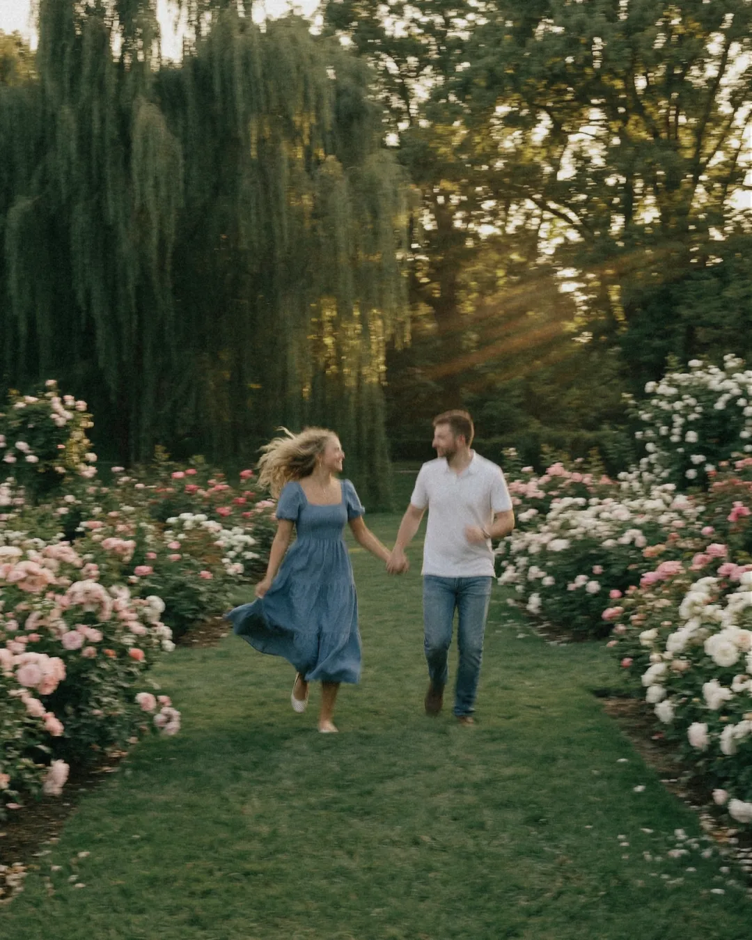Couple courant main dans la main dans une roseraie, campagne Florilège
