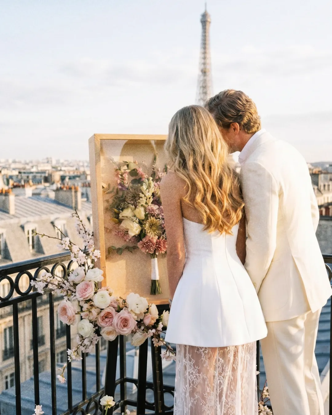 Mariés sur un balcon au-dessus des toits de Paris, cadre de fleurs préservées