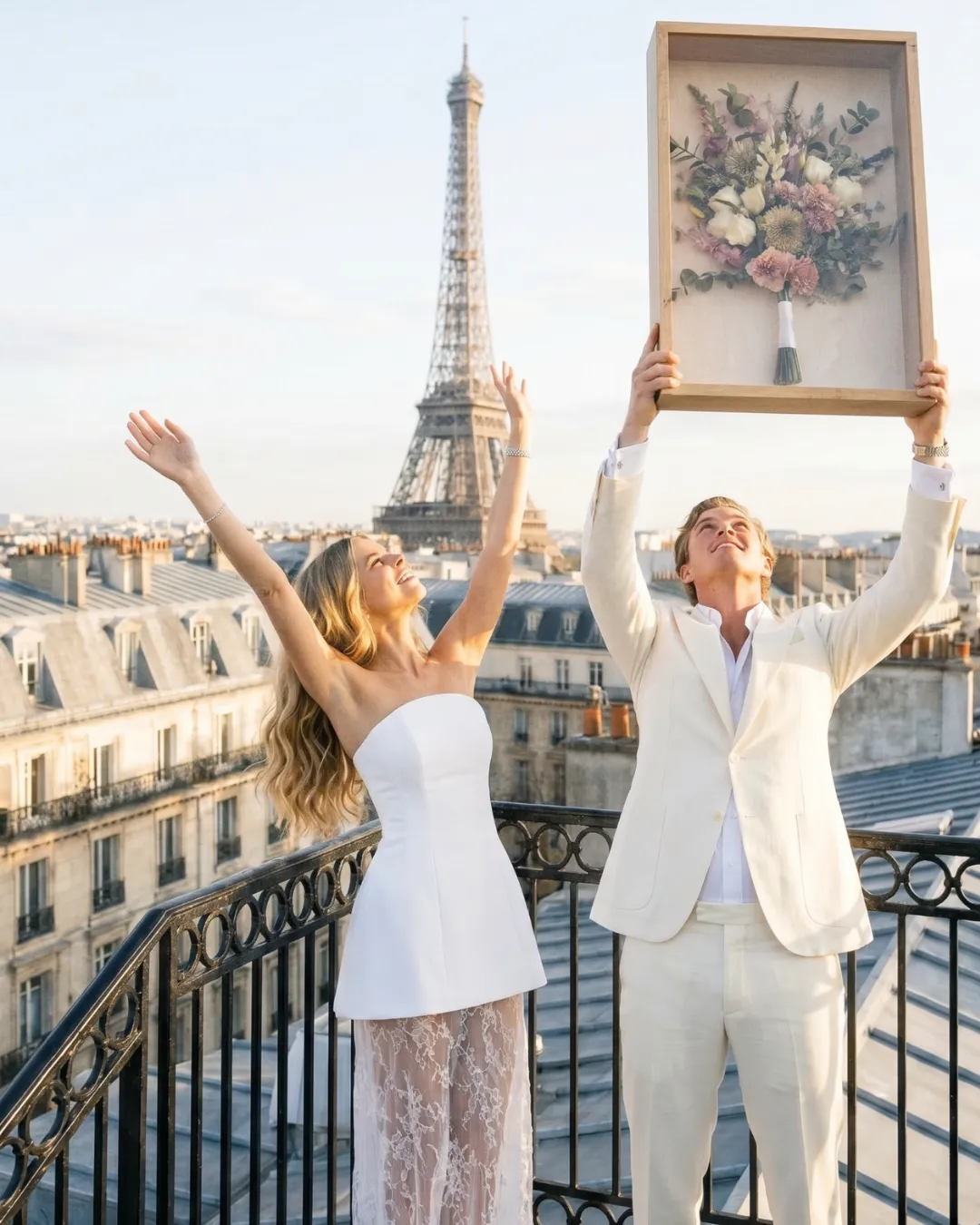 Mariés qui célèbrent au champagne sur un toit de Paris à côté du bouquet préservé