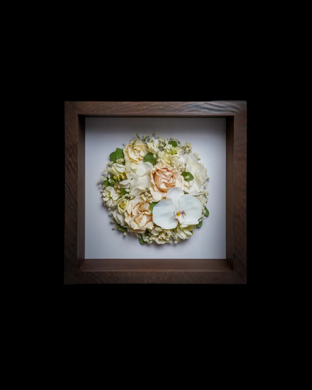 Bouquet de mariée préservé dans un cadre en bois, photographie produit sur fond noir
