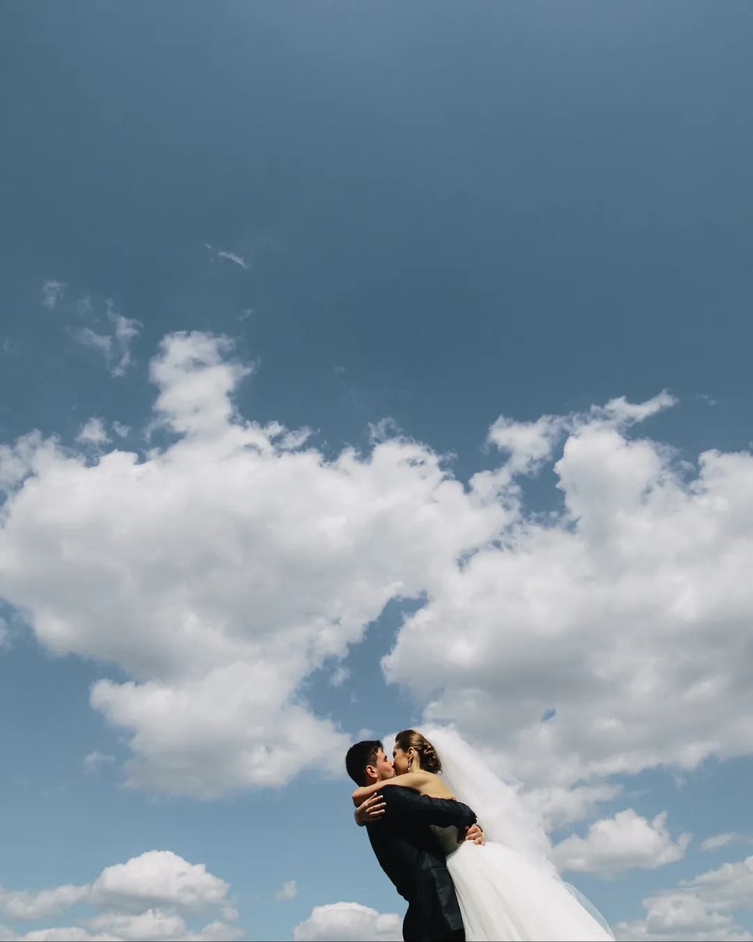 Mariés qui s'embrassent sous un grand ciel nuageux, direction artistique Studio Falida