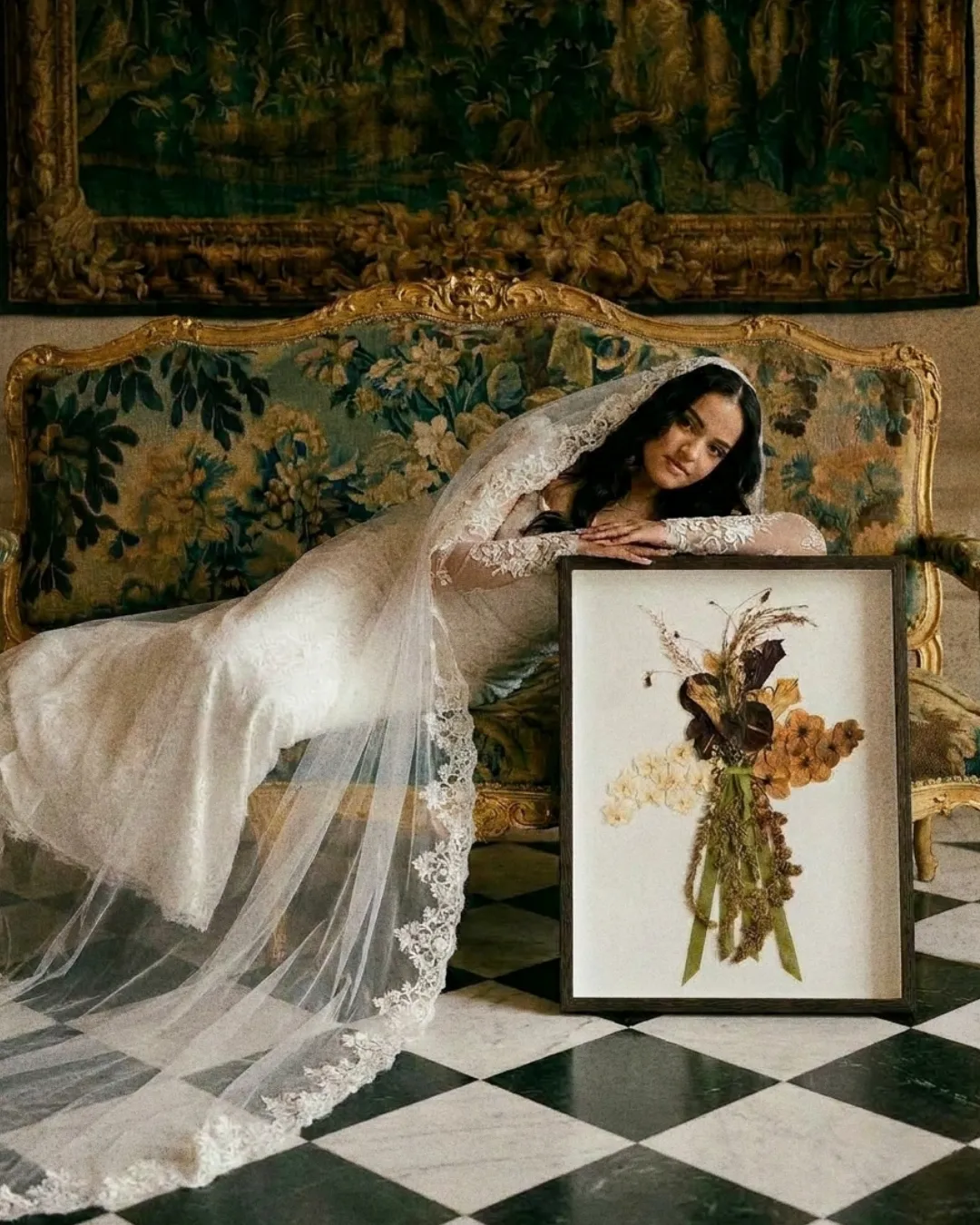 Mariée allongée sur un sofa ancien, accoudée au cadre floral